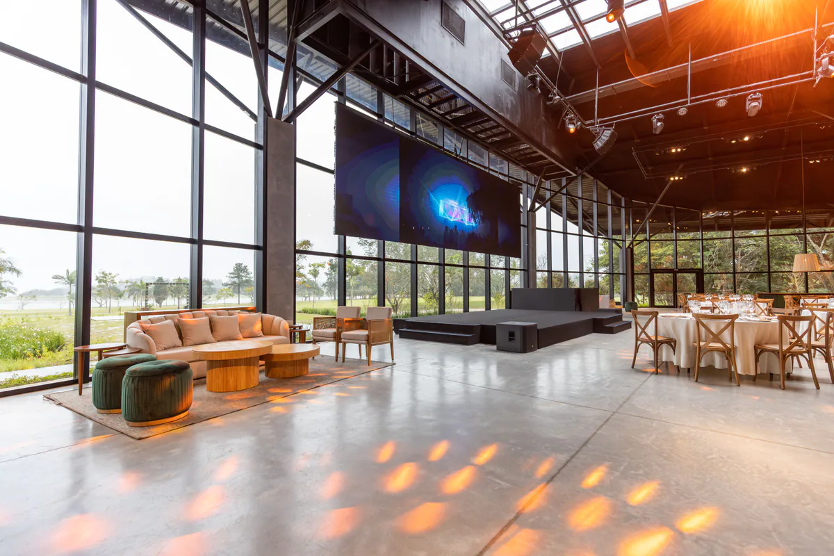 Grand espace événementiel avec scène, écran et tables de réception